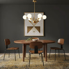 A Clérachic chandelier with white glass globes over a round walnut dining table, with a geometric painting on a dark grey wall.