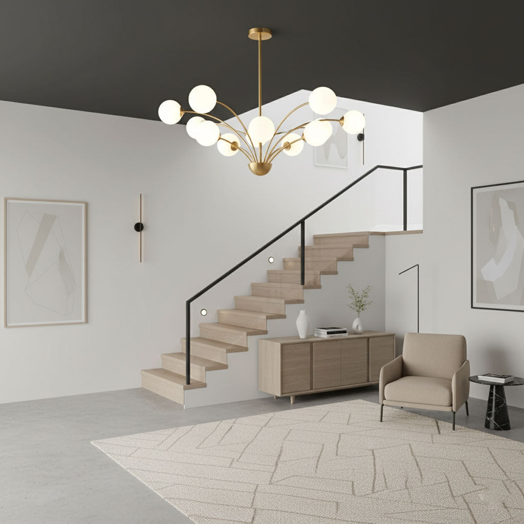 A Clérachic brass chandelier with white globes in a double-height hall, with an open timber staircase and a beige armchair below.