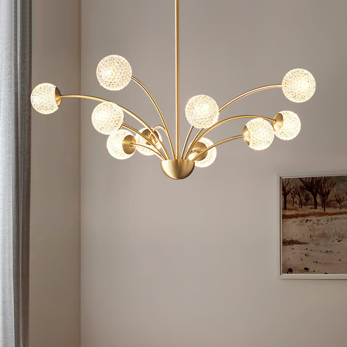 Looking up at this Clérachic chandelier, its textured globes glowing on curved brass arms against a soft taupe wall and a framed landscape.