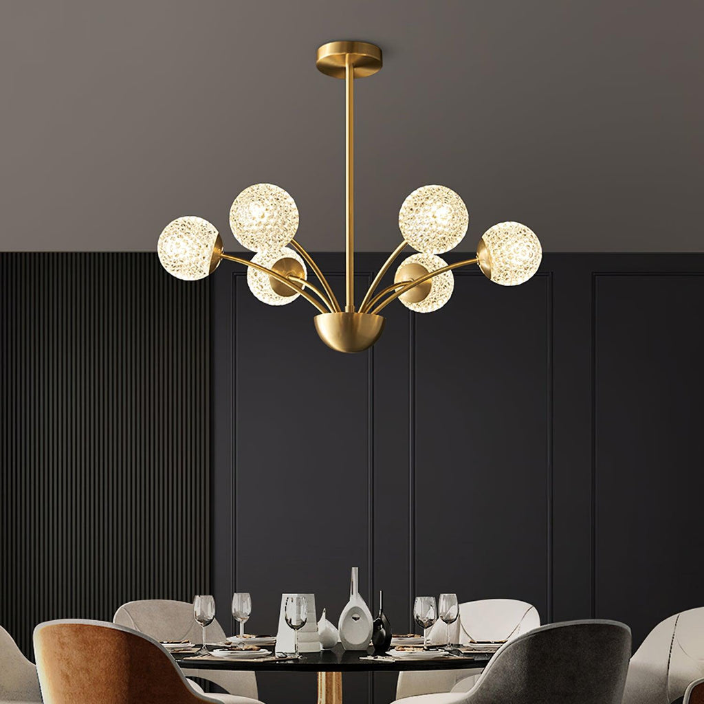 Eight lit textured globes on a Clérachic brass chandelier, hung above a laid dining table before dark panelling.