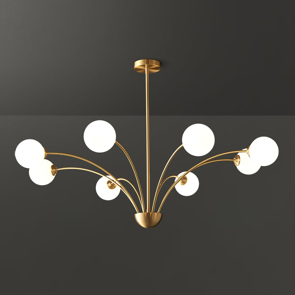 A larger Clérachic brass chandelier with white globes on long curving arms, shown against a dark grey studio backdrop.