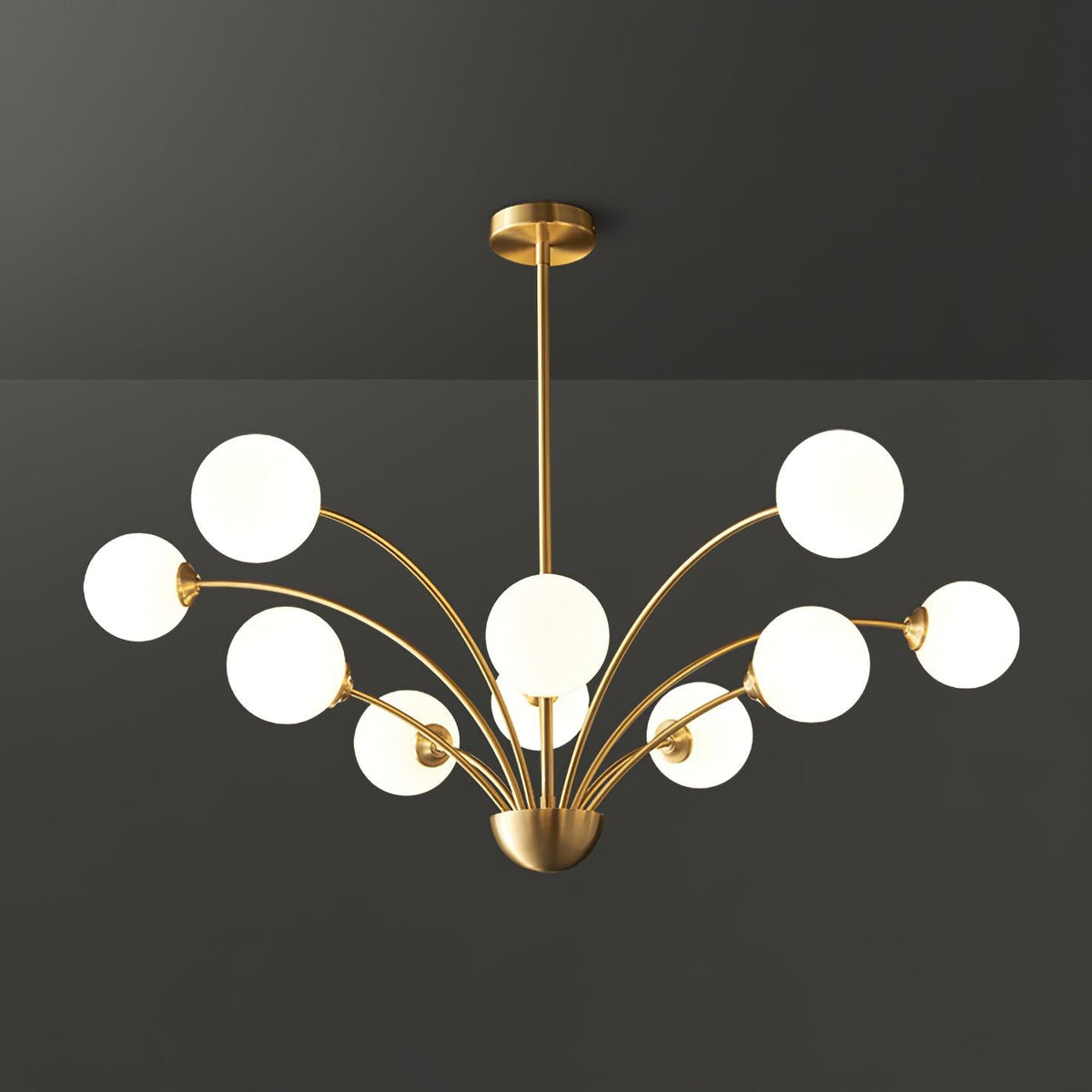 A Clérachic chandelier with eight white globes and a brass rod, seen straight on against a dark grey backdrop.