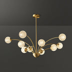 A Clérachic brass chandelier with textured globes in a clustered arrangement of varied arm heights, against a dark grey backdrop.