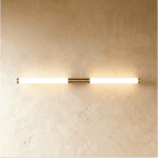 Clérachic linear LED wall light in a longer length, its frosted tube lit warm either side of a brass centre mount.