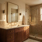 Two Clérachic slim vertical wall lights flanking a brass-framed vanity mirror above a walnut washstand in a tiled bathroom.