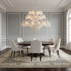 A white and clear-crystal version of this Clérachic chandelier hangs over a round dark table in a grey panelled dining room.