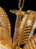 Close view of the rope-twist stem and glowing brass leaves of this Clérachic chandelier, against a black background.