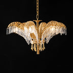 A Clérachic chandelier in lit brass and clear crystal, hung on a gold chain against a black backdrop.