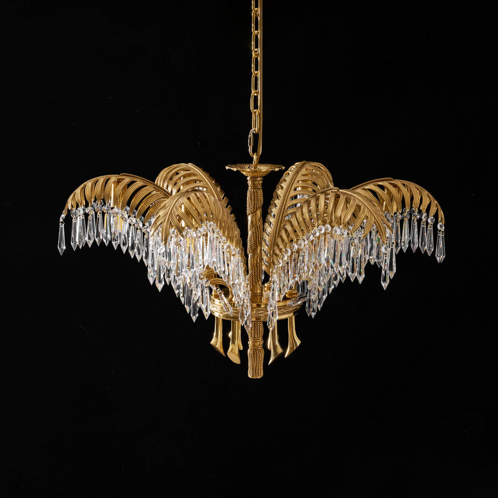 Lit Clérachic chandelier in brass with long crystal drops, hanging on a chain against black.