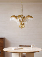 Clérachic brass chandelier hung at ceiling height above a round stone-topped table, with a wooden cabinet at the left.