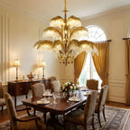 Tiered Clérachic chandelier in brass and crystal, hung beside tall curtains above a polished dining table and a sideboard with lamps.