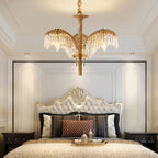 Above a tufted cream headboard in a panelled bedroom, a Clérachic chandelier shows its brass stem and crystal-fringed leaves.