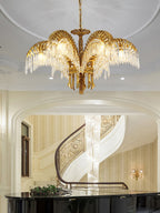 Clérachic brass chandelier hanging in a stair hall, with a spiral staircase and a black piano in the background.
