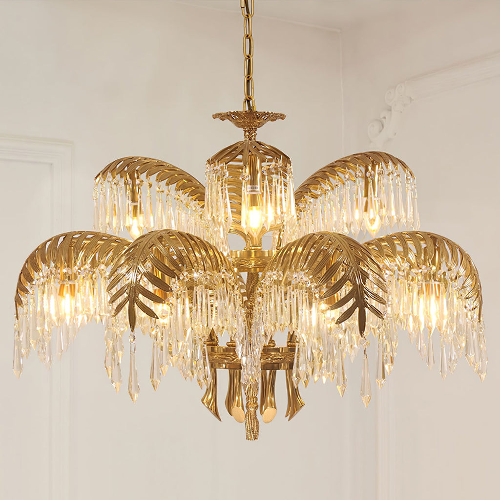 Close, front-on view of this Clérachic chandelier in gold brass, its upper and lower tiers of leaves hung with clear crystal drops.