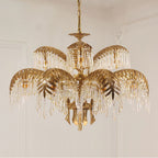 Larger tiered Clérachic chandelier in gold brass, with leaf-shaped tiers and long crystal drops against a pale panelled wall.