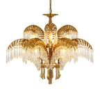 Gold brass palm leaves and crystal drops of this Clérachic chandelier on a white background, with brass tassel-like drops below.