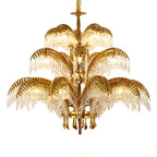 Three tiers of brass palm leaves with crystal fringe on this large Clérachic chandelier, shown against white.