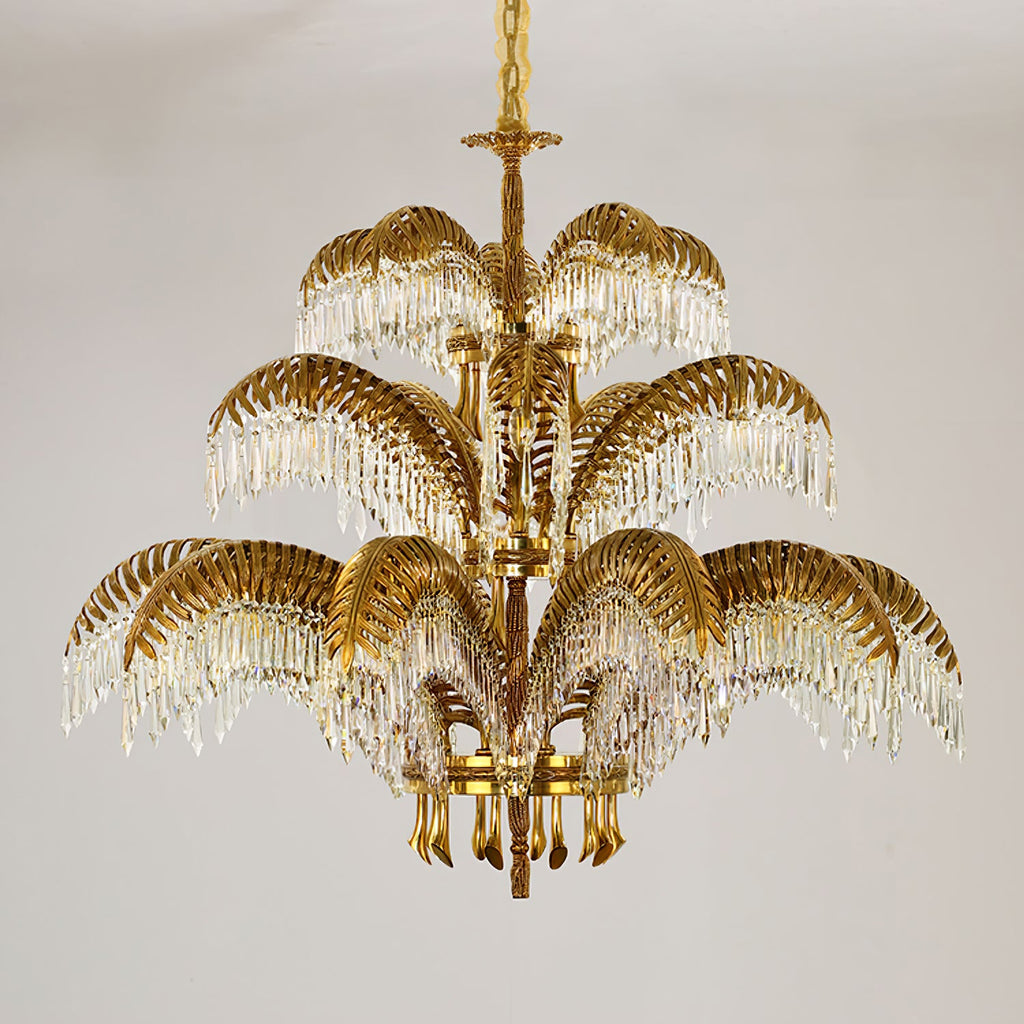 Three stacked tiers of brass leaves and crystal drops make up this Clérachic chandelier, hung from a gold chain.
