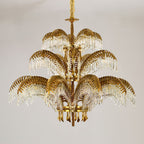 Three stacked tiers of brass leaves and crystal drops make up this Clérachic chandelier, hung from a gold chain.