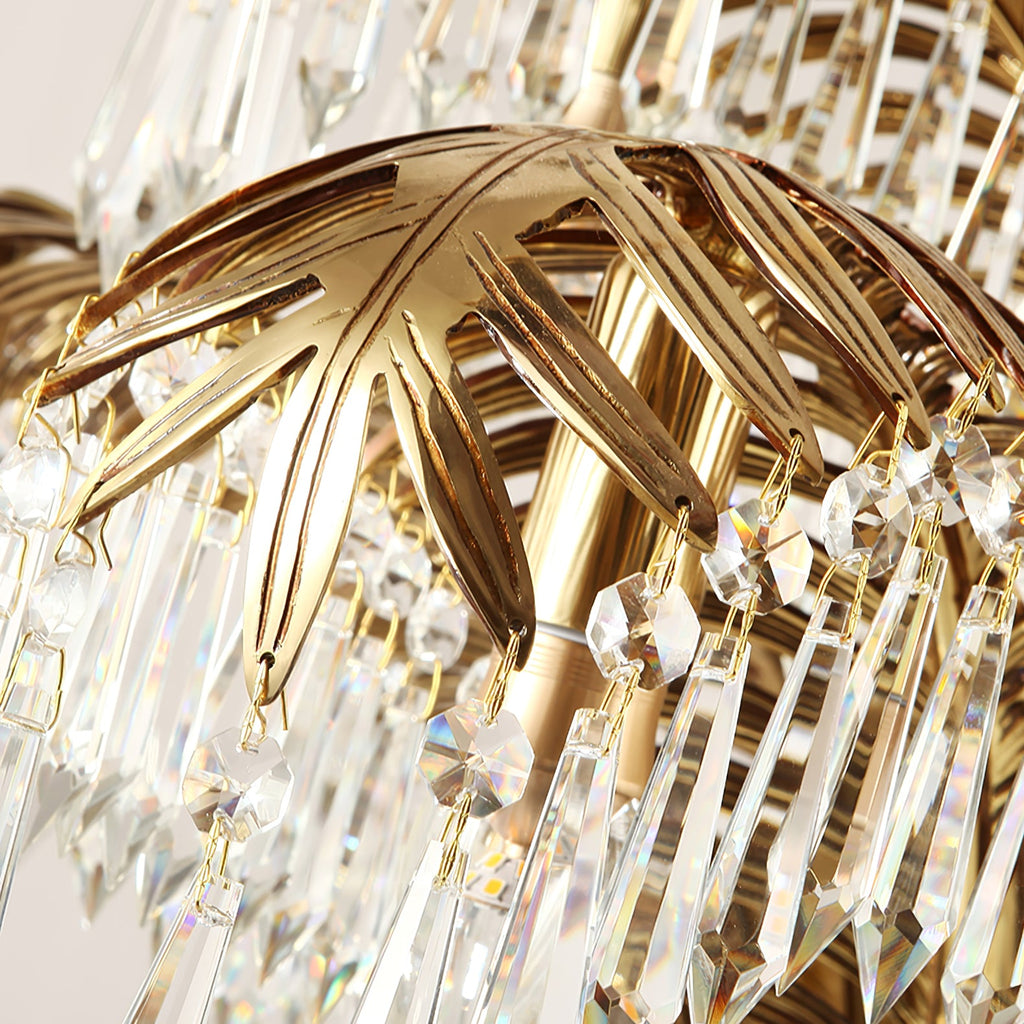 Close view of a brass palm leaf and the cut crystal drops on this Clérachic chandelier.