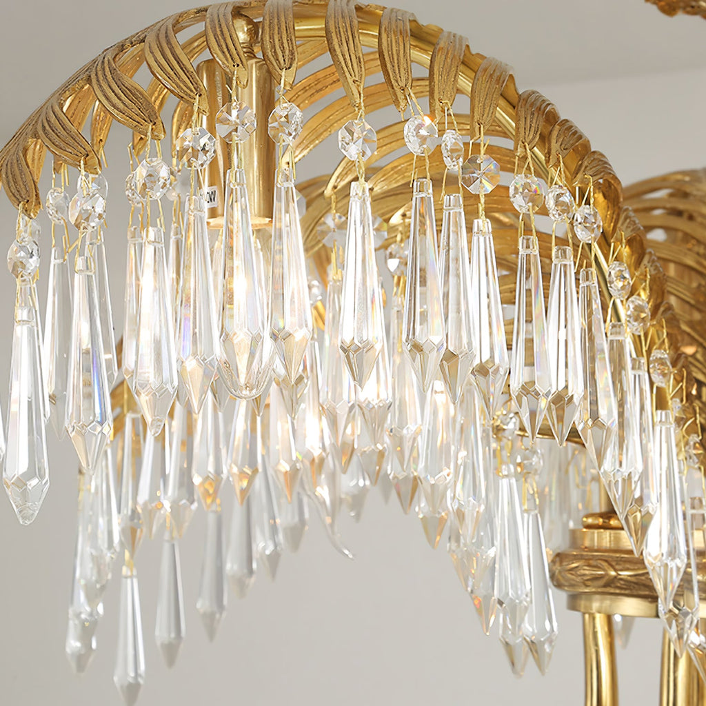 Close view of the ribbed brass leaf arch and the long clear crystal drops hanging from it on this Clérachic chandelier.