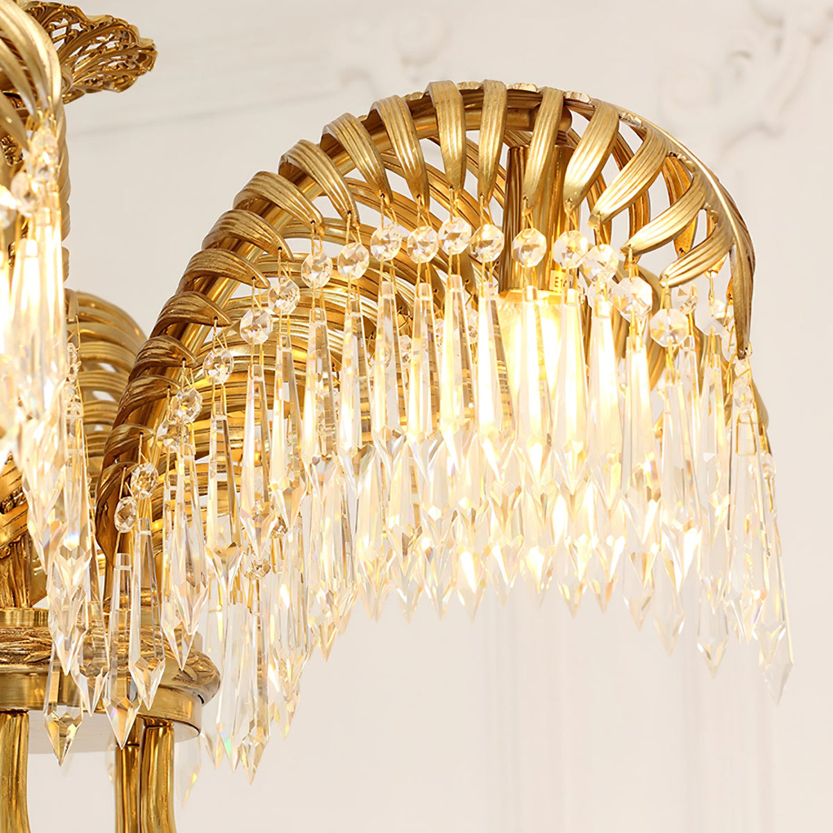 Close view of one lit brass leaf with crystal drops and small faceted beads on this Clérachic chandelier.