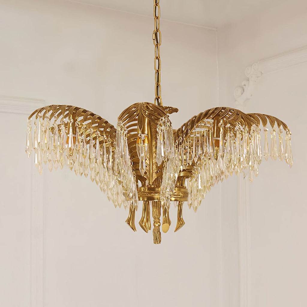 A compact Clérachic brass chandelier with crystal-fringed leaves hangs on a chain against a pale panelled wall.