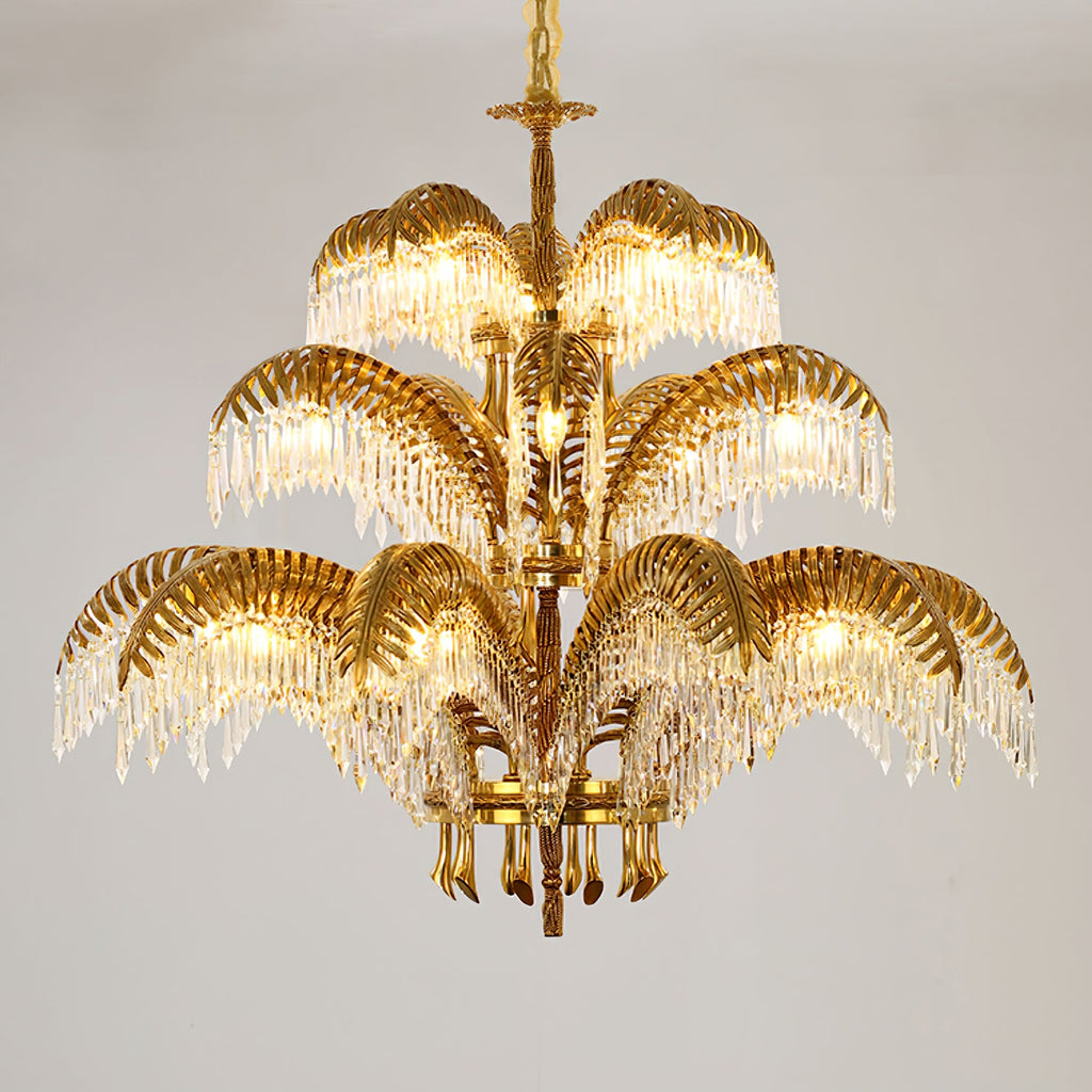 Gold brass Clérachic chandelier in three tiers with crystal drops, on a soft grey backdrop.