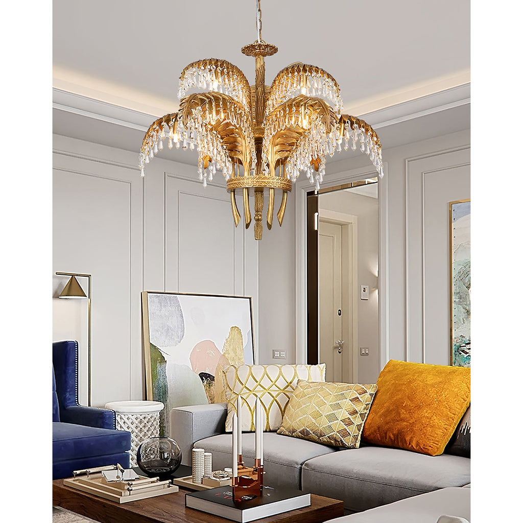 A Clérachic brass chandelier hangs in a grey living room with a blue armchair, an orange cushion and abstract art.
