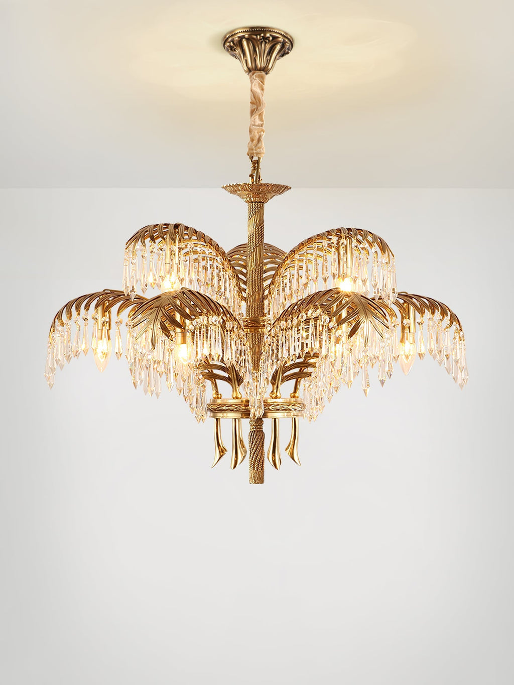 A two-tier Clérachic chandelier with a bronze ceiling plate and cord-wrapped stem, lit warmly on a pale background.