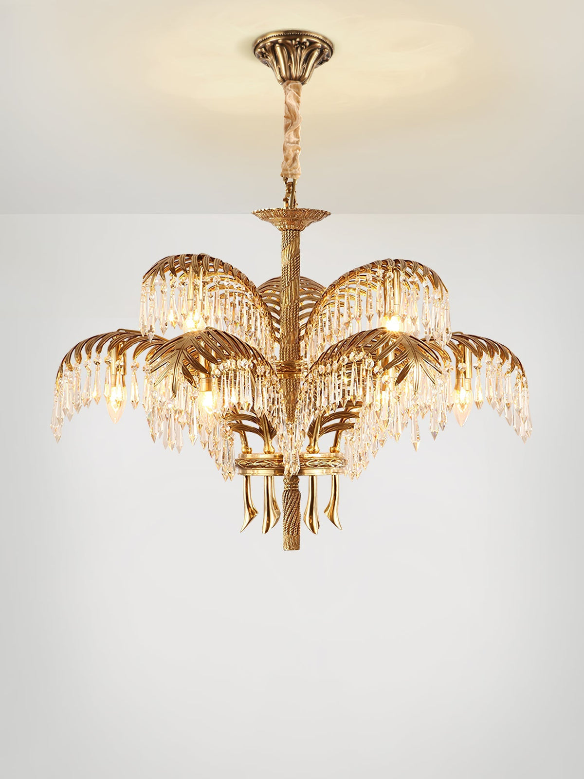 A two-tier Clérachic chandelier with a bronze ceiling plate and cord-wrapped stem, lit warmly on a pale background.