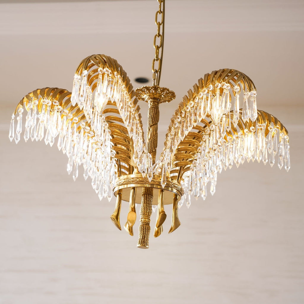 Close, low view of a Clérachic chandelier with gold brass leaves, crystal drops and a rope-twist stem.