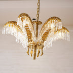 Close, low view of a Clérachic chandelier with gold brass leaves, crystal drops and a rope-twist stem.