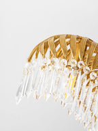 Close view of a brass leaf arch with a row of clear crystal drops on this Clérachic chandelier.