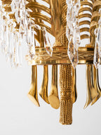Close view of the brass base ring, curved tails and rope-twist finial under this Clérachic chandelier.