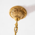 Underside of the carved brass ceiling plate that holds this Clérachic chandelier on its gold chain.