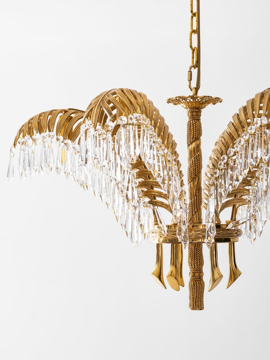 Angled view of a Clérachic brass chandelier with a gold chain, crystal-fringed leaves and a rope-twist stem.