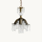 Clérachic pendant with a bronze palm-leaf canopy and clear crystal drops, hung on a chain against a plain white backdrop.