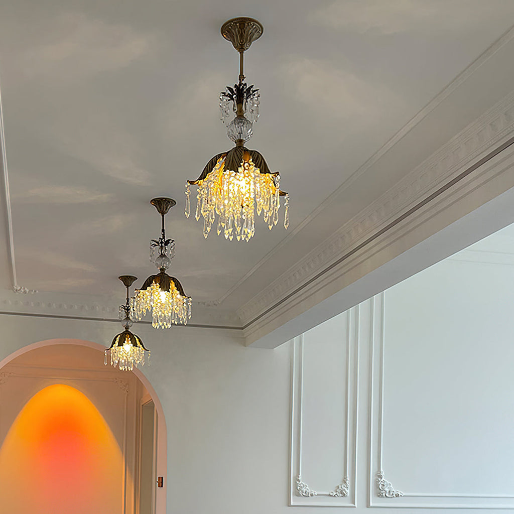 Three Clérachic crystal pendants of descending height glow warm below a cornice, with an arched doorway beyond.