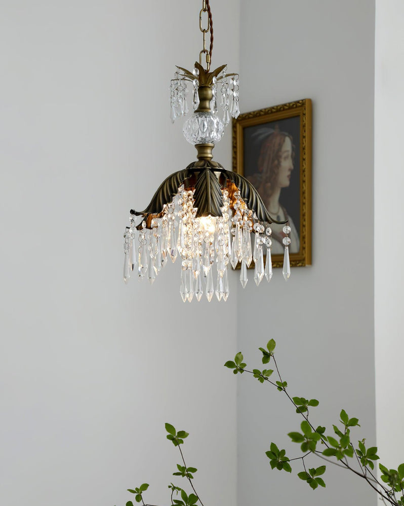 Lit Clérachic pendant with a bronze leaf shade and crystal drops hangs next to a portrait, with a green sprig at the left.
