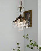 Lit Clérachic pendant with a bronze leaf shade and crystal drops hangs next to a portrait, with a green sprig at the left.