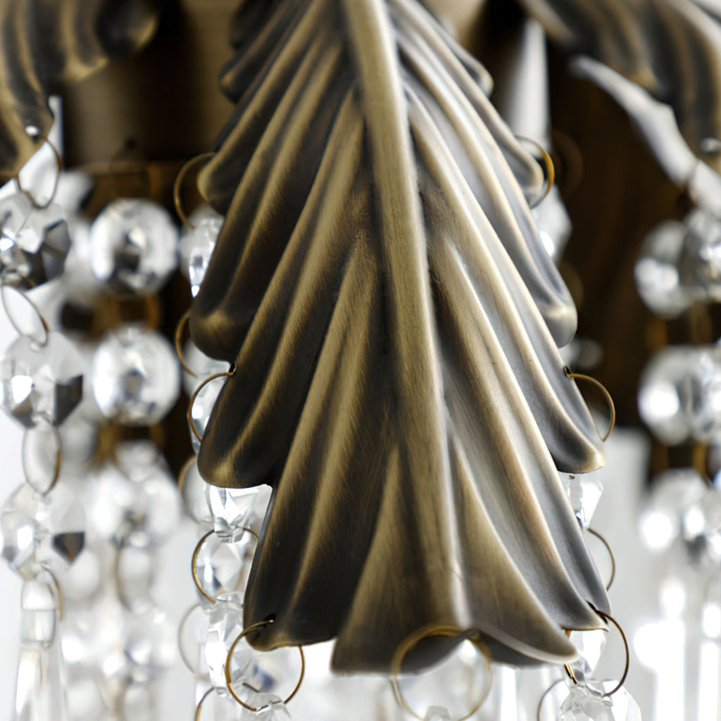 Close view of a bronze palm leaf on this Clérachic pendant, with linked crystal beads hanging around it.