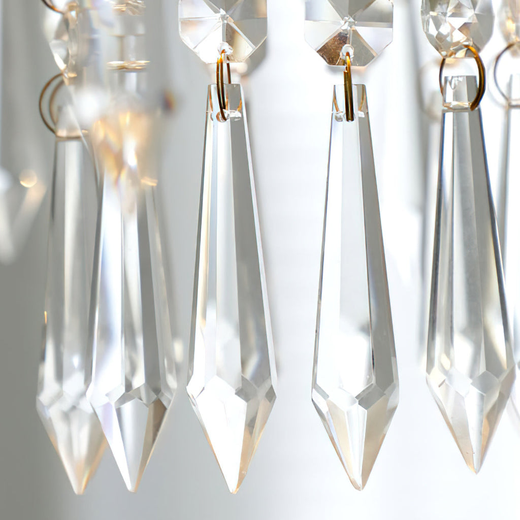 Close view of clear, pointed crystal drops with gold-toned rings on this Clérachic pendant, lit from behind.