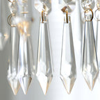Close view of clear, pointed crystal drops with gold-toned rings on this Clérachic pendant, lit from behind.