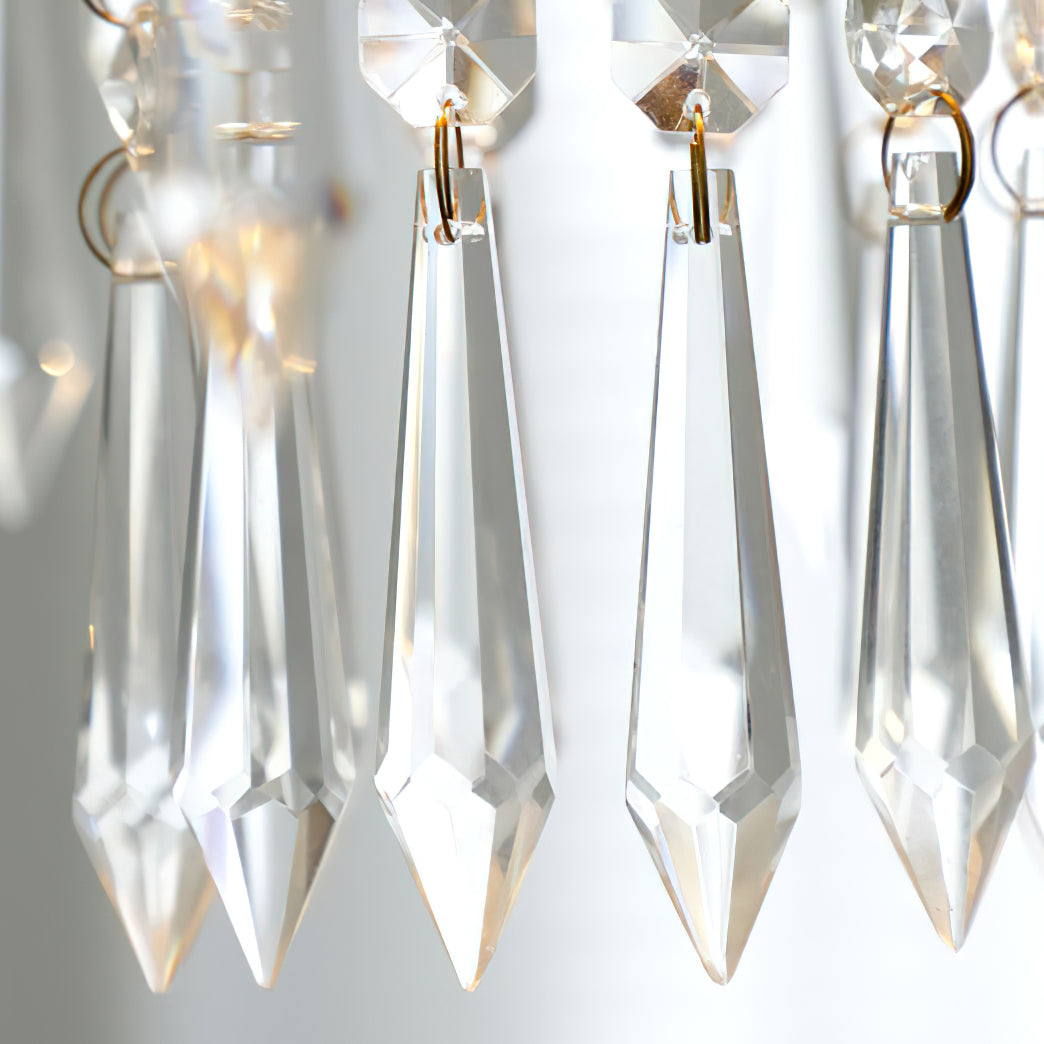 Close view of clear, pointed crystal drops with gold-toned rings on this Clérachic pendant, lit from behind.