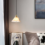 A Clérachic Xen pendant lights a nightstand vignette with framed art, dried florals, and a quilted headboard.