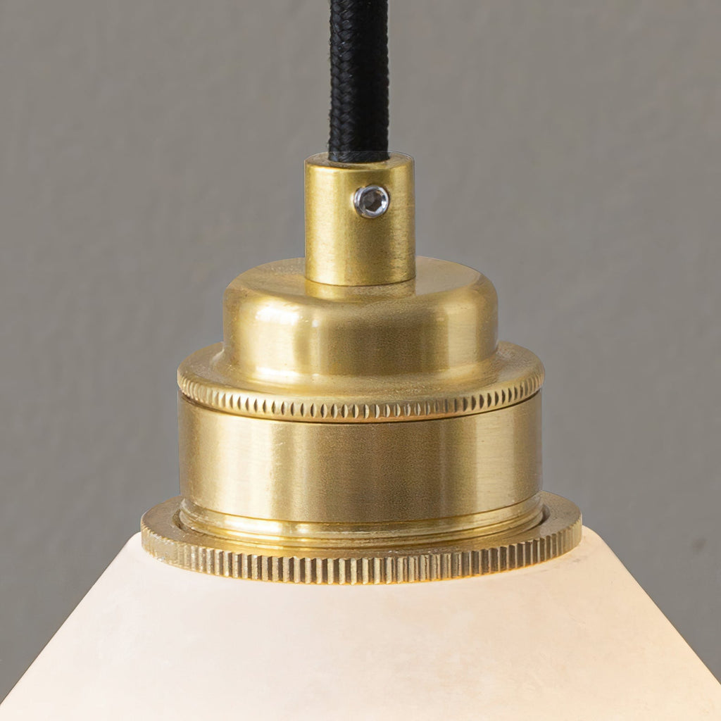 Macro shot of the Clérachic Xen pendant's knurled brass fitting and cable entry above the alabaster shade.