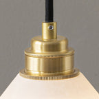 Macro shot of the Clérachic Xen pendant's knurled brass fitting and cable entry above the alabaster shade.