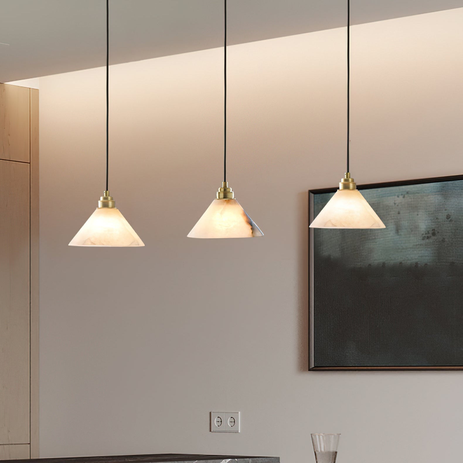 Three Clérachic Xen pendants hang in a row above a kitchen counter, lighting the space beside a framed abstract print.