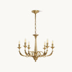 A brass candle-style Clérachic chandelier with six arms, a tapered column and a hanging chain, on a plain white backdrop.